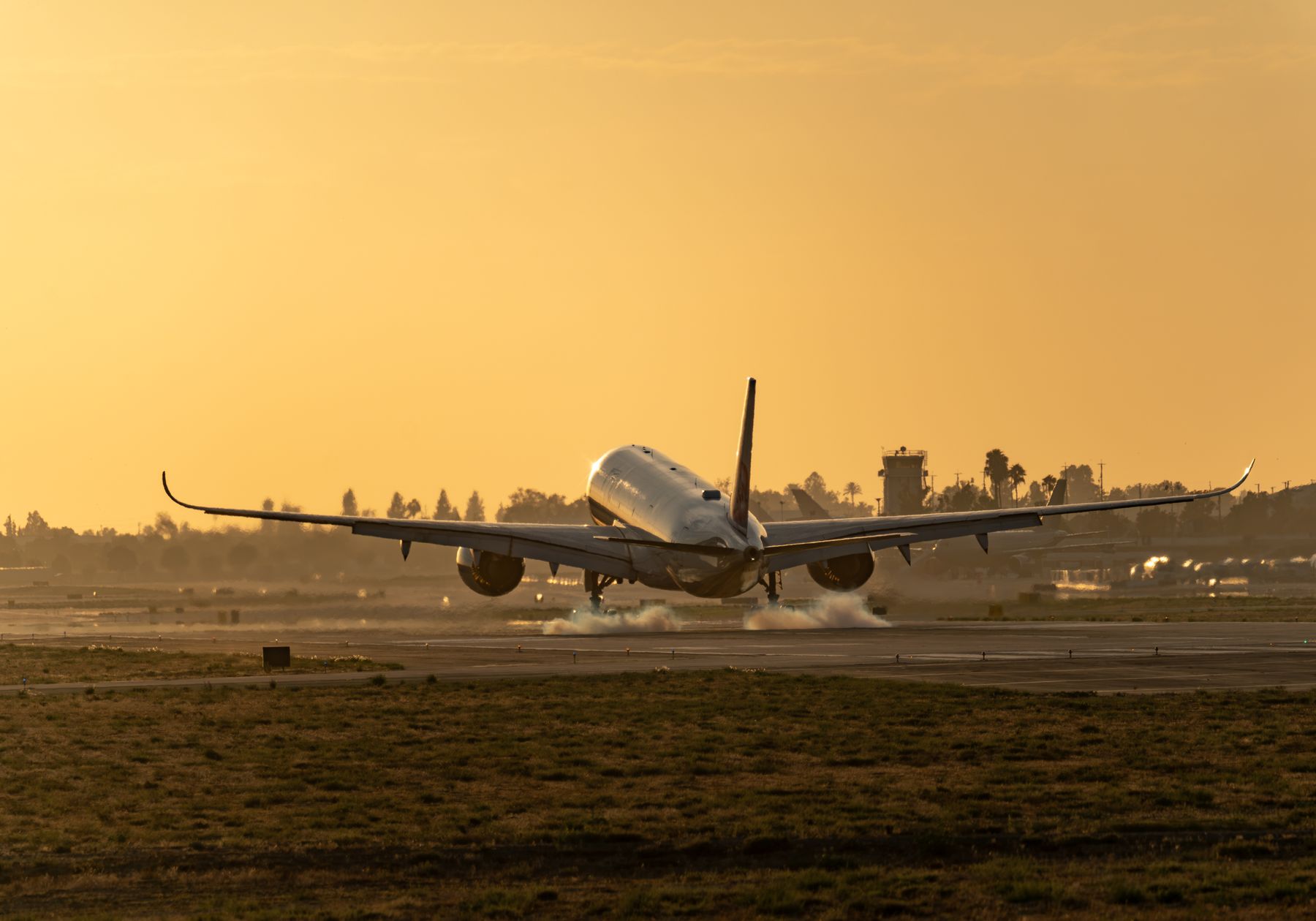 A passenger jet landing on a runway at sunset