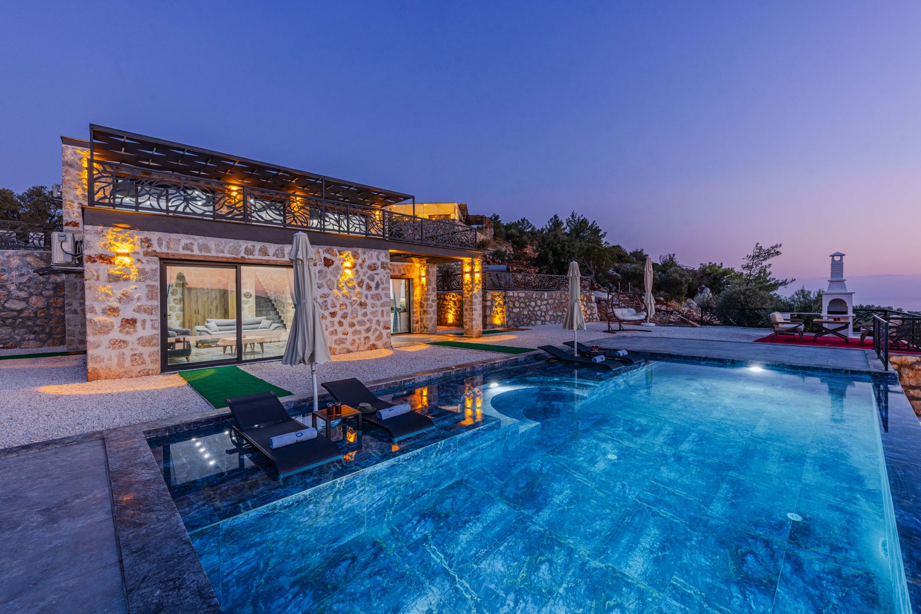 A stone villa with a lit pool at twilight