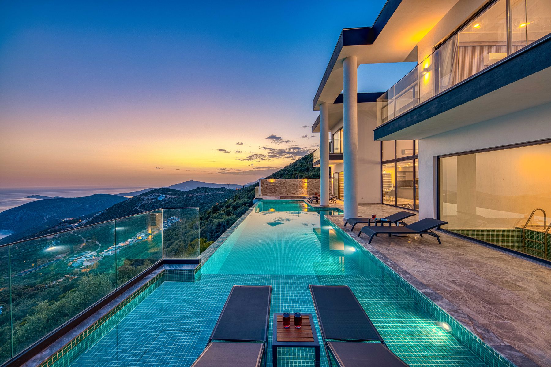 A villa with an infinity pool above the sea at sunset