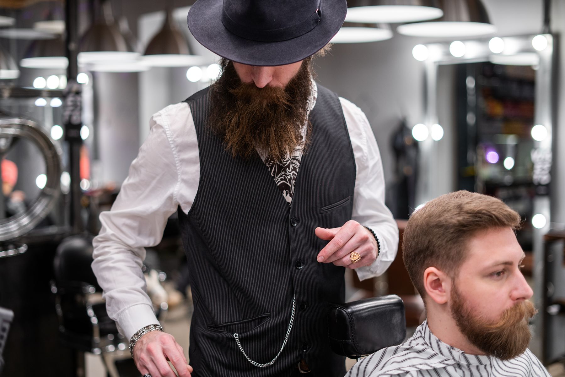 A barber in a hat working on a client's hair
