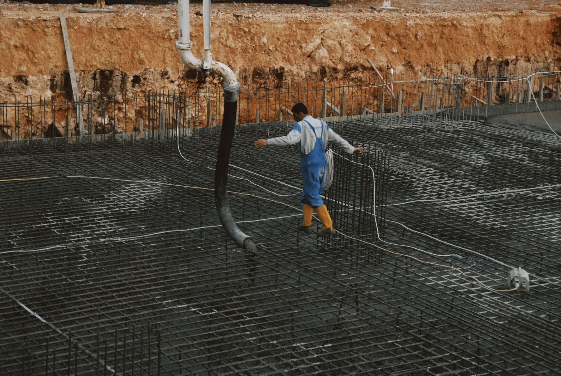 A worker tying rebar on a foundation