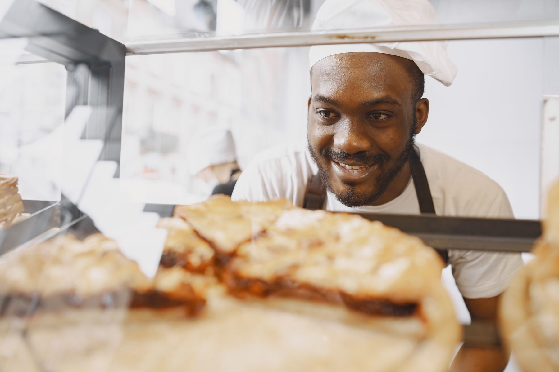A baker behind a counter of pastries