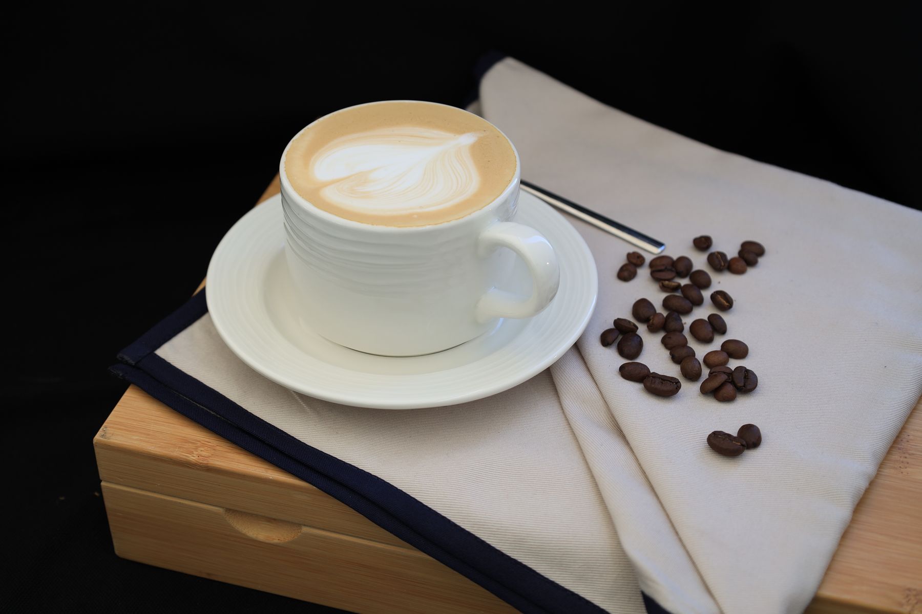 A coffee cup with latte art and beans