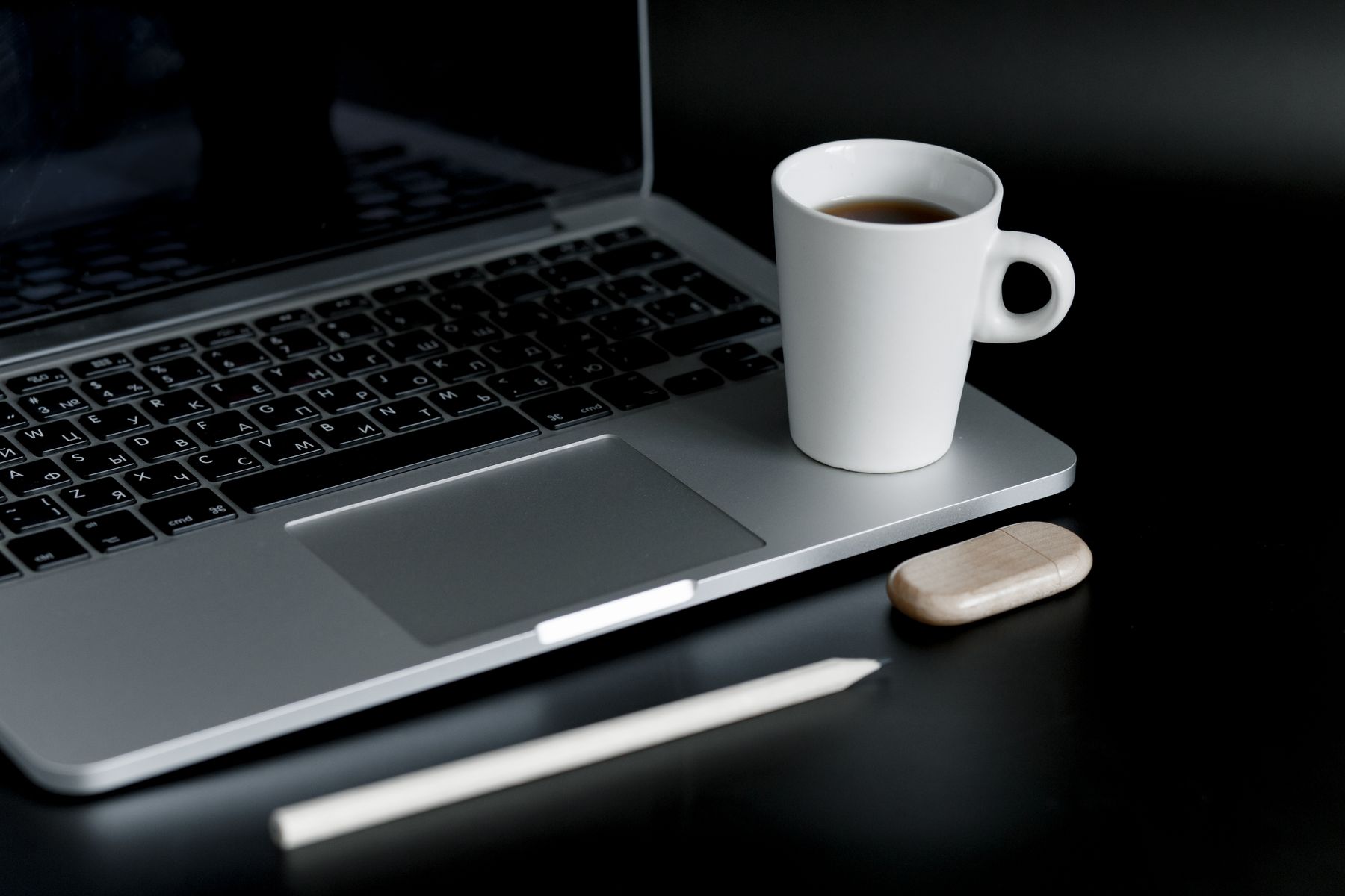 A laptop and coffee cup on a dark desk