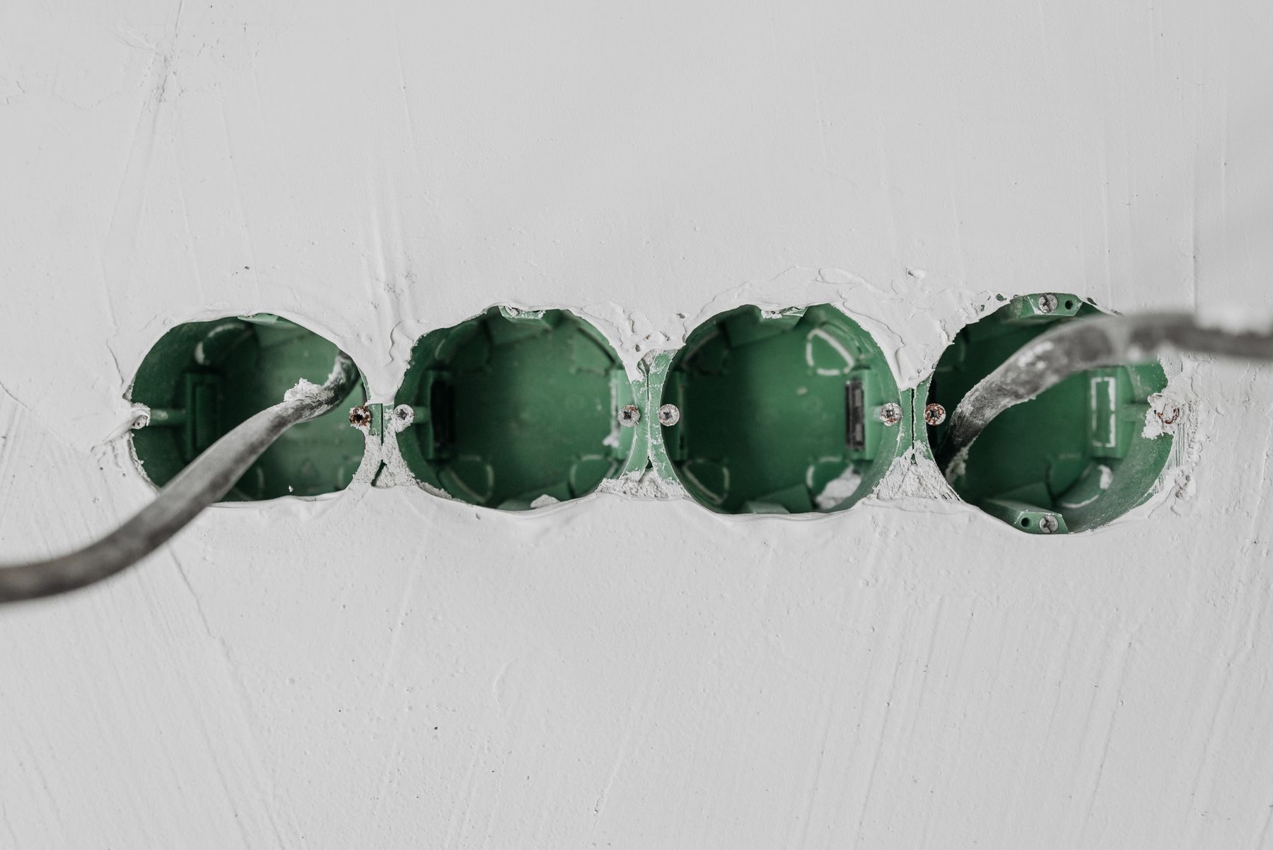 Green electrical boxes set into a white wall