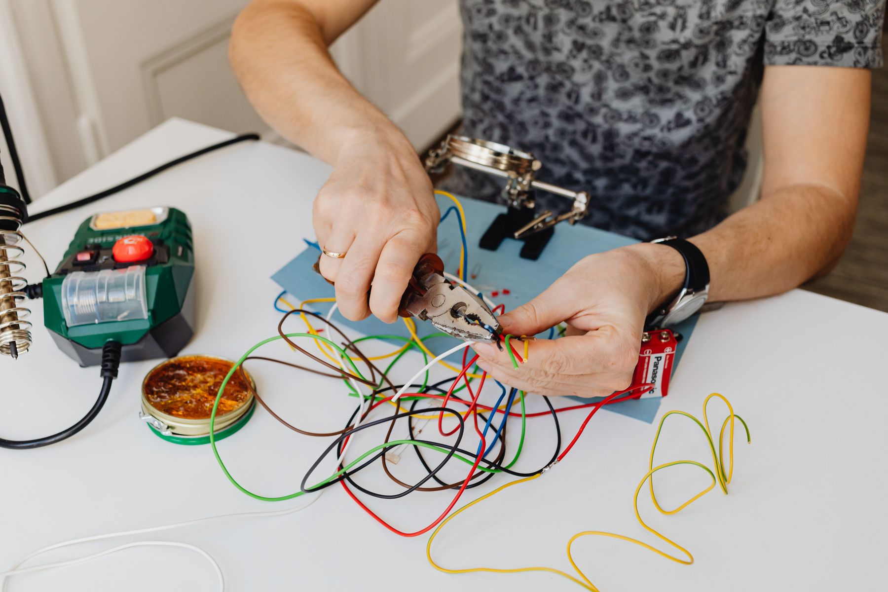 Hands stripping coloured wires at a bench