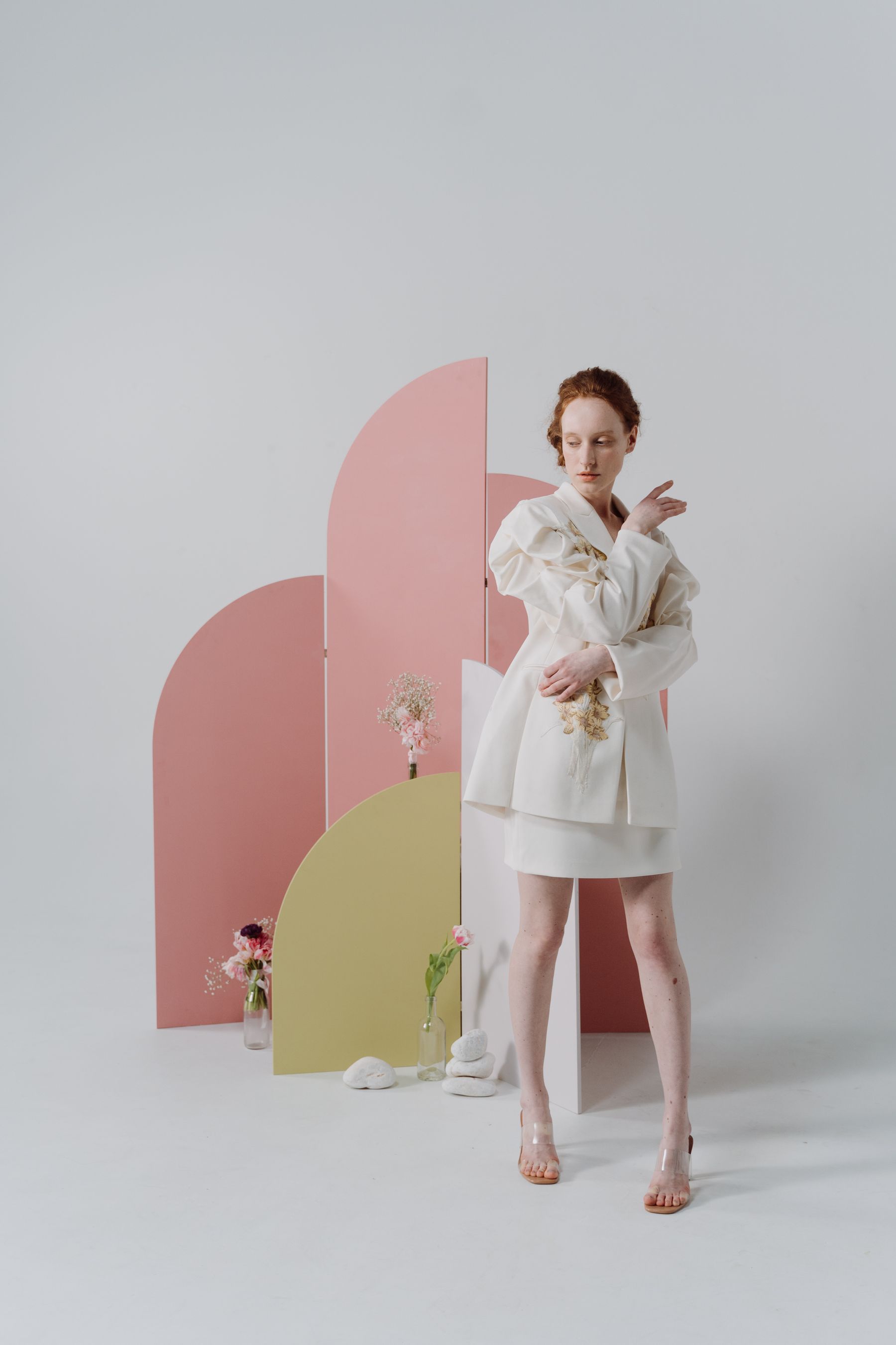 An ivory fashion look in a pastel studio setting