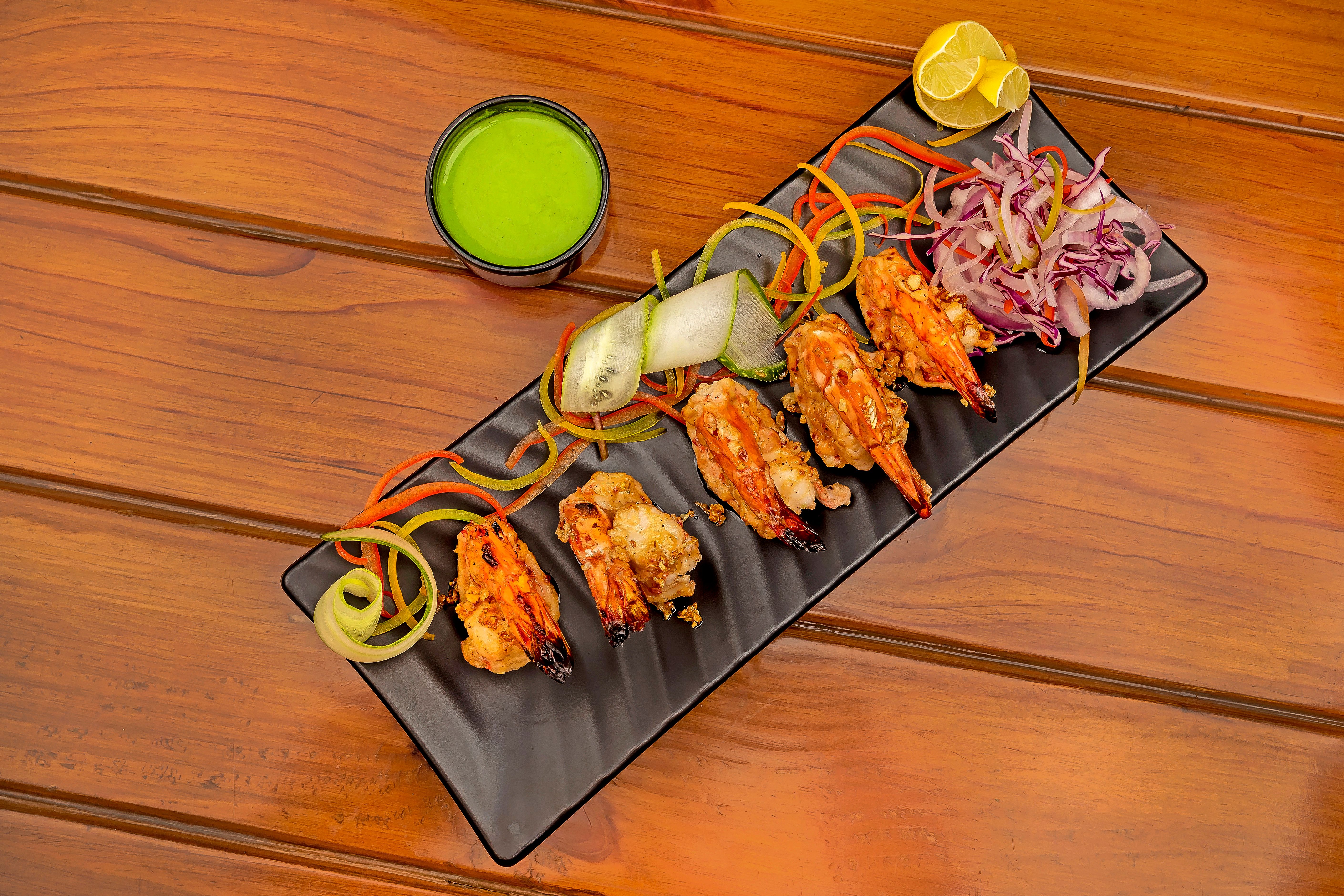 Grilled prawns with vegetables and sauce on a dark plate